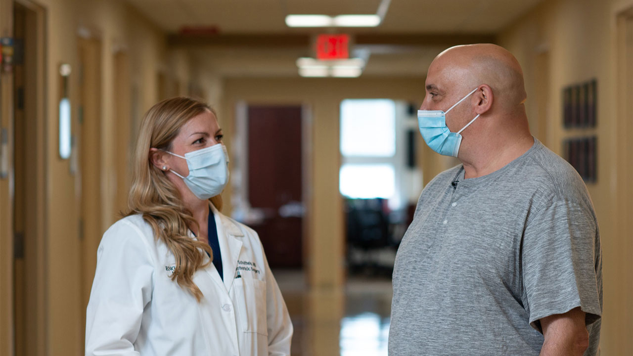 a woman doctor with long blonde hair speak to her male patient. 