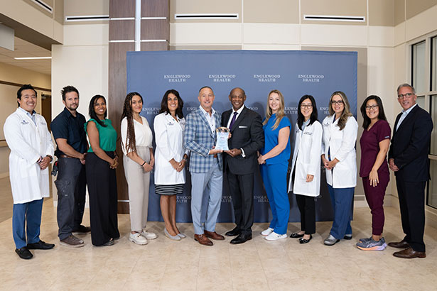 Englewood Health president and CEO Warren Geller and AHA regional executive Michael Draine flanked by the health system’s team members.