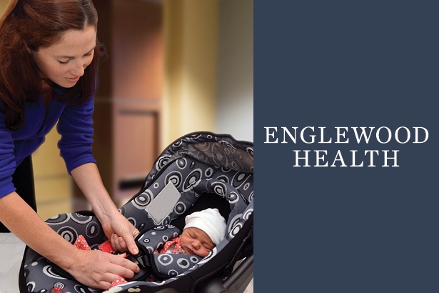 mom placing new born in car seat with EH logo