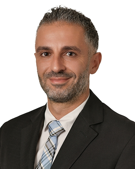 male with black suit and blue plaid tie and cream color shirt