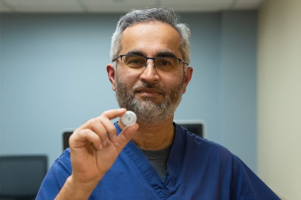 man in blue scrubs holding watchman flx device